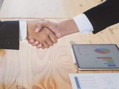 Two business people shaking hands at a table.