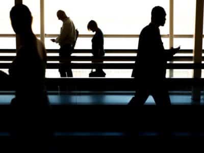 Silhouettes of people walking in an airport.