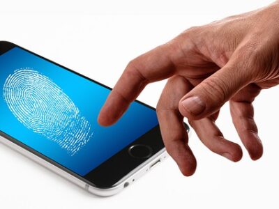 A person's hand touching a smartphone with a fingerprint on it.