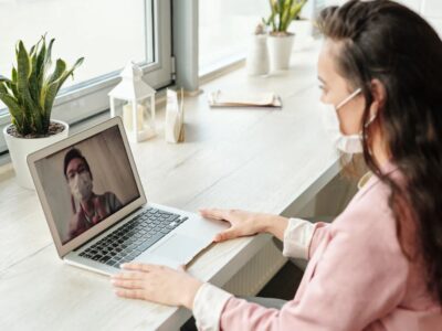 A woman is using a laptop while wearing a face mask.