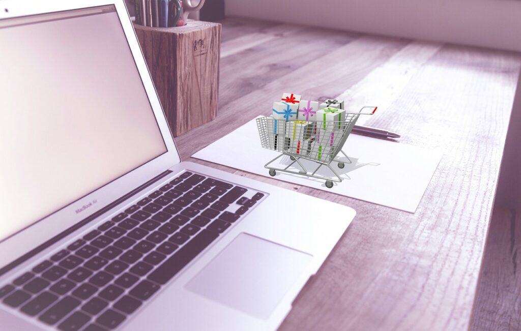 A picture of a miniature shopping next to a laptop, representing the search for the best ERP system for ecommerce.