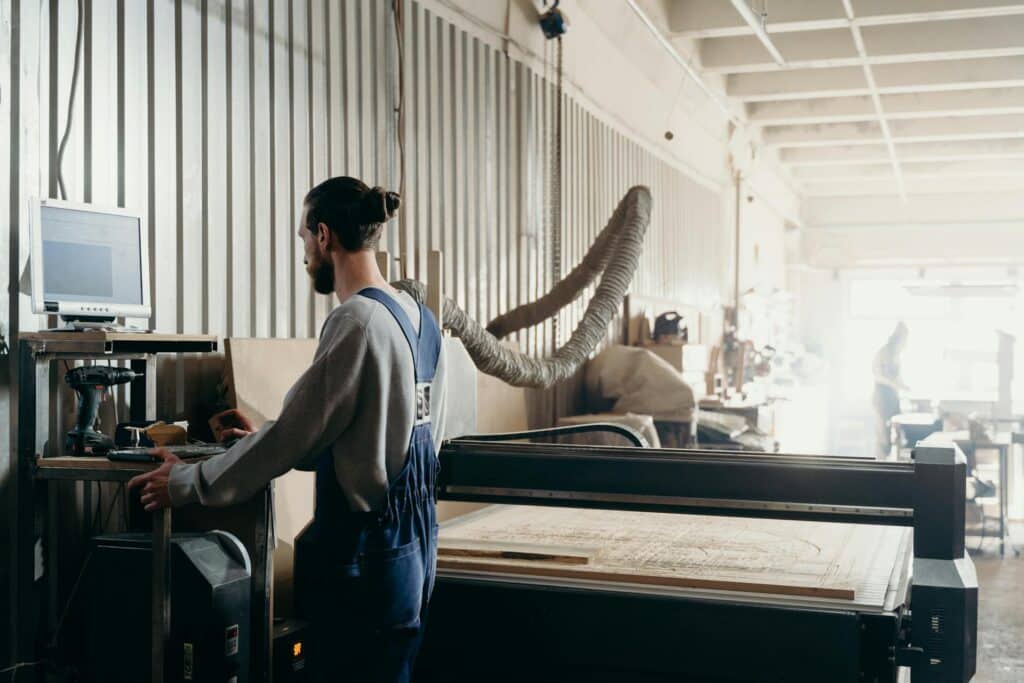 Man working on a computer screen with manufacturing software in an industrial facility.