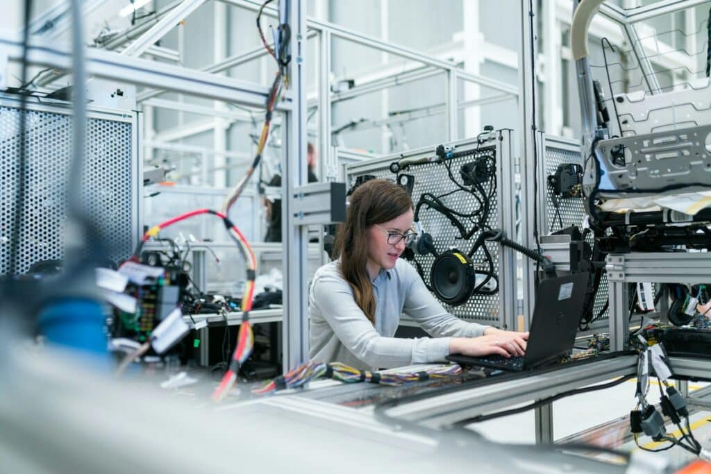 Women on laptop in center of advanced manufacturing facility using Sage Intacct for operations and accounting