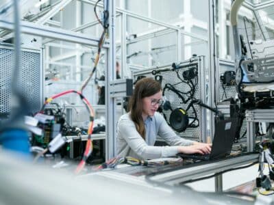 Women on laptop in center of advanced manufacturing facility using Sage Intacct for operations and accounting