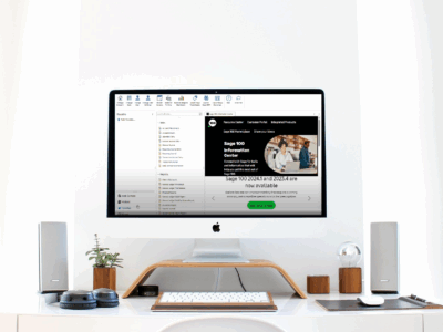 Computer monitor displaying Sage 100 ERP software interface with the Favorites navigation panel open on the left side, showing various folders and menu items, positioned on a clean white desk with minimal accessories.