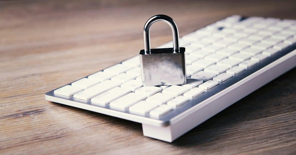 Silver padlock sitting on white computer keyboard on wooden desk, symbolizing cybersecurity and data protection with NIST compliance.