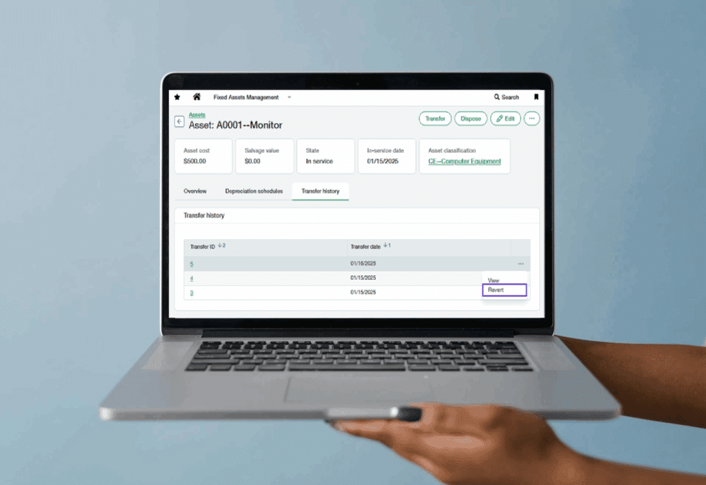 Sage Intacct Fixed Assets Management interface updated with 2025 R2 and displaying asset details including cost, depreciation schedules, and transfer history on a laptop screen being held up by a pair of hands from the right of the screen.