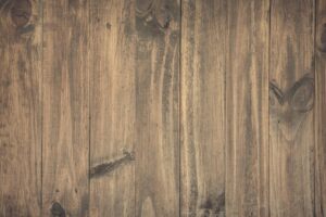 Weathered wooden lumber planks with natural grain patterns and knots, showing vertical wood board texture in brown and tan tones