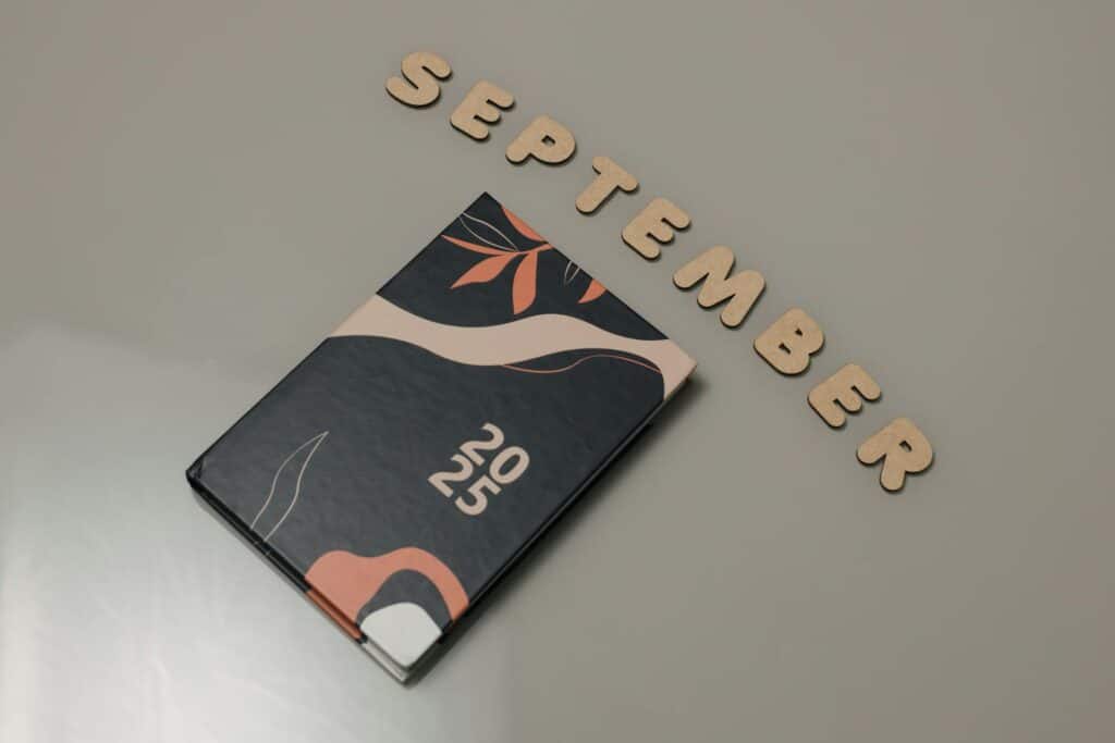 Wooden letter blocks spelling "SEPTEMBER" arranged beside a 2025 journal on neutral background for SWK's cybersecurity news recap article.