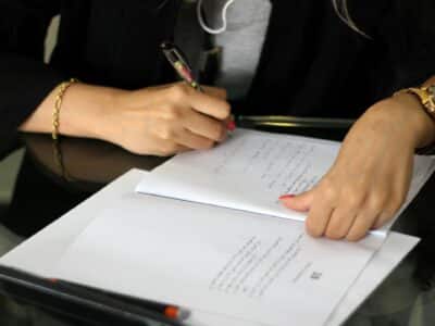 Business professional reviewing and annotating cybersecurity compliance documents with handwritten notes for threat assessment evaluation.