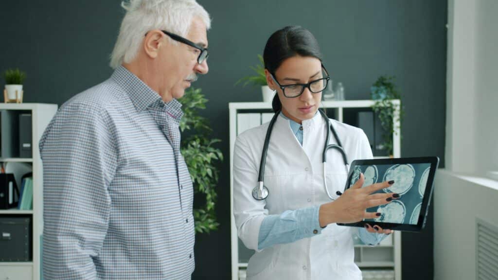 Healthcare professional reviews medical imaging on tablet with patient in modern clinic