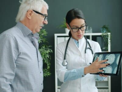 Healthcare professional reviews medical imaging on tablet with patient in modern clinic