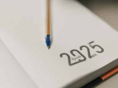 A notebook opened to a blank page marked "2025" with a pen placed across it, representing preparation for Sage 100 year-end closing procedures and tax reporting for the upcoming fiscal year.
