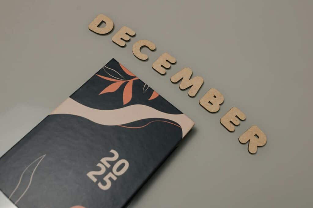 Wooden letters spelling "December" arranged above a 2025 calendar with decorative leaf design for SWK Technologies cybersecurity news recap