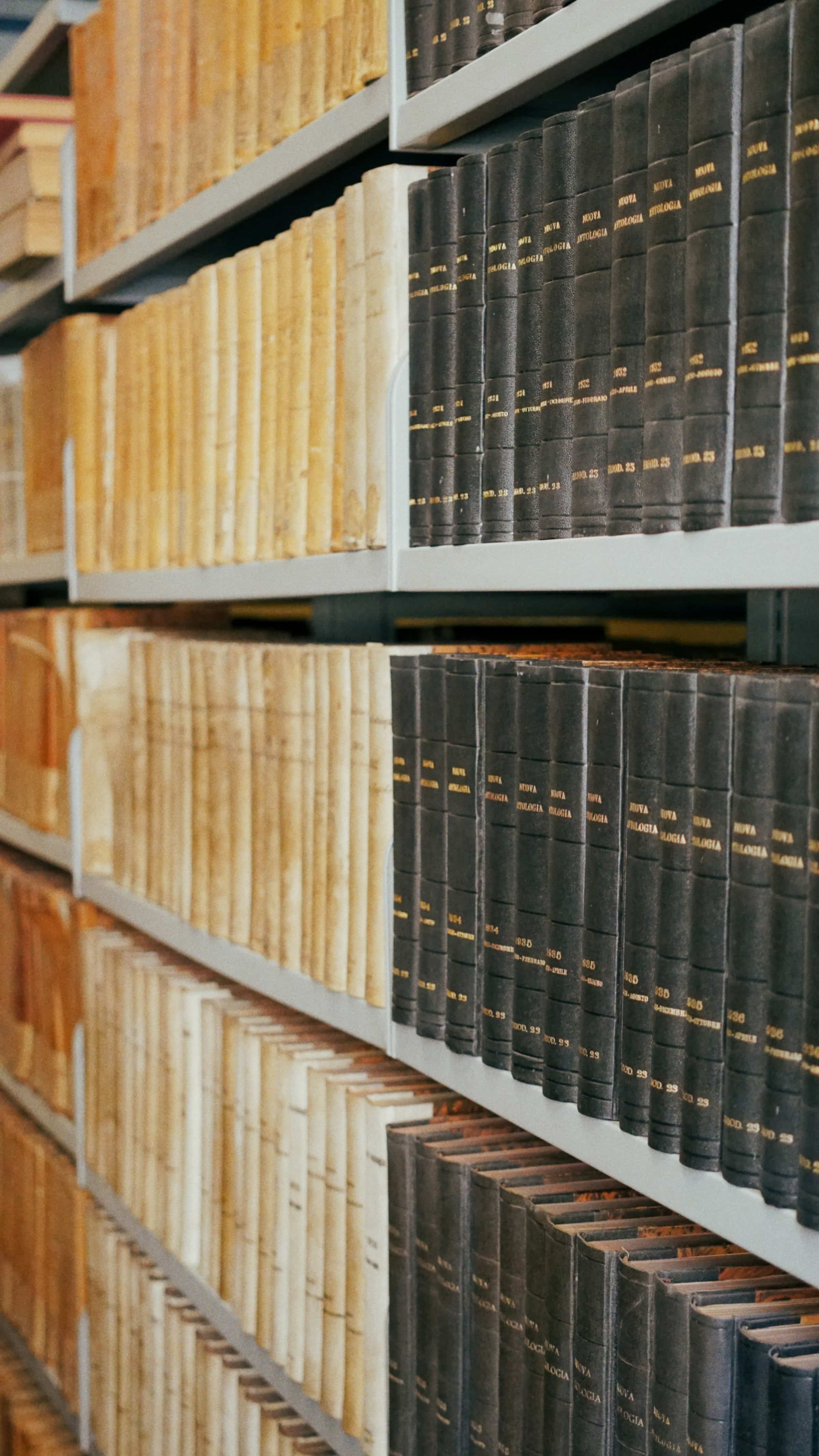 Rows of aged leather-bound legal volumes on wooden library shelves, representing the regulatory frameworks addressed by SWK Technologies' cybersecurity compliance services