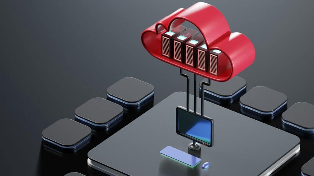 3D illustration of a red cloud icon containing five server racks suspended above a black desktop computer monitor and devices on a dark surface, with cables connecting the servers to the monitor.