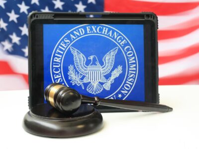 Black gavel resting on a sound block in front of a tablet displaying the Securities and Exchange Commission seal, with an American flag in the background.