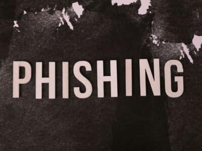 Wooden block letters spelling PHISHING on a dark, mottled black and white textured surface.